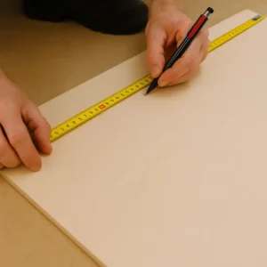 Close-up of hands marking wood with a pencil and measuring tape – precision layout for custom carpentry and home renovation work.